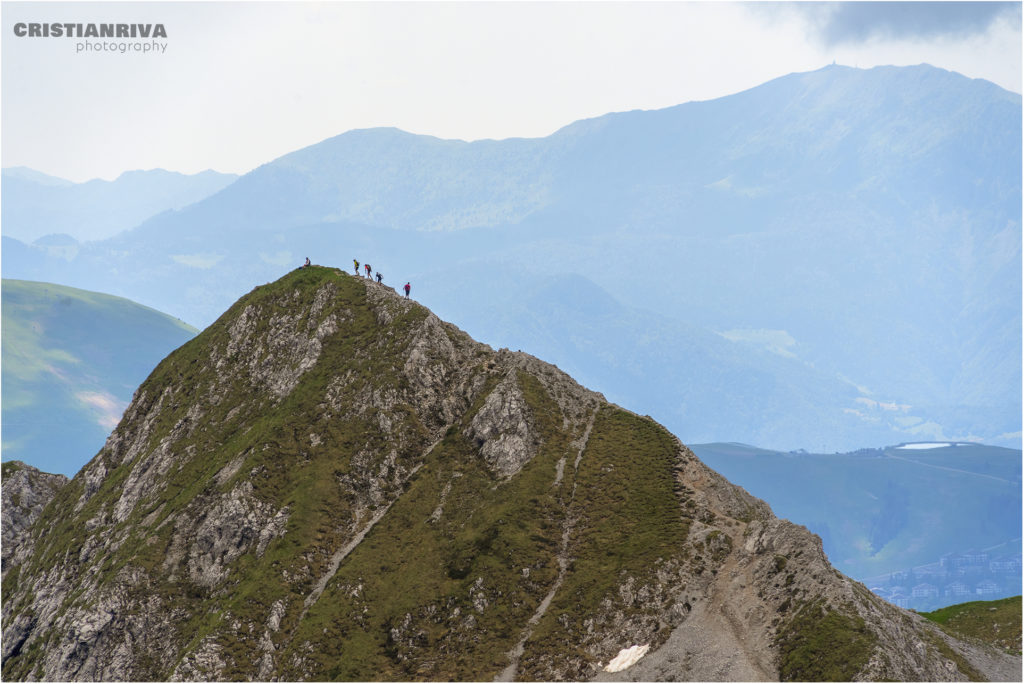 Pizzo Corzene: uni sguardo alle spalle con escursionisti sulla cima del pizzo Corzene